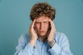 Young curly man with headache rubbing his temples