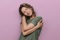 Young curly woman hugging herself, looks happy, loves herself, has high self esteem Royalty Free Stock Photo