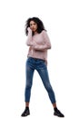 Young curly woman in jeans, pink sweater, posing