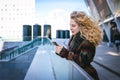 Young curly woman using her phone and relax in the city Royalty Free Stock Photo