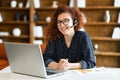 Young curly woman wearing wireless headset using a laptop computer for communication Royalty Free Stock Photo