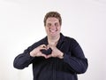 Young curvy man posing in a white background isolated smiling and showing a heart shape with hands Royalty Free Stock Photo