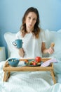 Young curvy woman taking a breakfast on the bed with cup of coffee and croissant Royalty Free Stock Photo