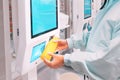 Young customer woman buys and pays for a bottle of orange juice at the checkout of a self-service vending machine in a