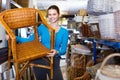 Young customer woman standing with wicker chair in shop for decor Royalty Free Stock Photo