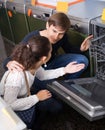 Young customers choosing new dish washing machine in appliance s Royalty Free Stock Photo