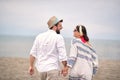 Young cute adult couple at beach, holding hands, looking each other, laughing Royalty Free Stock Photo