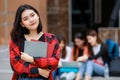 Young and cute Asian college student girls holding books, pose to camera with group of friends blur in background in front of Royalty Free Stock Photo