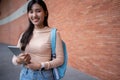 Young and cute Asian college student girls smile carrying a backpack with a textbooks in front of the university campus building. Royalty Free Stock Photo