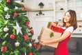 Young cute Asian girl holding X`Mas present boxes, Christmas tree decorated with ornament at home living room