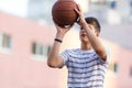 Young cute boy plays basketball at the outdoor streetball court on a sunny summer day. Teenager player in action dribbling