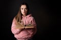 A young cute brunette in a pink hoodie, reading a book. Student with an open book in her hands, Royalty Free Stock Photo