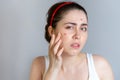 Young cute brunette woman examines her face with pimples. The concept of cosmetology and acne control, adolescence. Copy