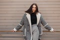 Young cute brunette woman in a trendy plaid jacket in a black T-shirt in stylish gray pants is resting standing Royalty Free Stock Photo