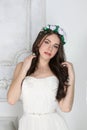 Young cute brunette in wreath and in white dress poses Royalty Free Stock Photo