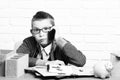 Young cute businessboy in grey sweater and glasses sitting at table with papers pink piggy pig bank holding and speaking Royalty Free Stock Photo