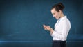 Young cute businesswoman close up portrait holding mobile phone in her hands and watching it. Isolated studio background Royalty Free Stock Photo