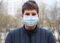 Young cute caucasian boy wearing protective mask against the corona virus on the street. Teenager in surgical face mask