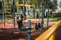 Active lifestyle concept. Young cute Caucasian man shakes his abs on street sports ground equipped with exercise equipment. Royalty Free Stock Photo