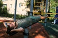 Active lifestyle concept. Young cute Caucasian man shakes his abs on street sports ground equipped with exercise equipment. Royalty Free Stock Photo