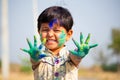 Young cute cheerful little girl kid with applied holi colors powder showing colorful hands to camera during holi festival Royalty Free Stock Photo