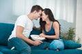 Young cute couple beautiful brunette woman and handsome man leaning to each other while watching movie on the sofa sweet