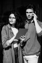 Young cute couple - a boy and a girl standing near a glass building. The couple spend time together. The guy speaks on the phone, Royalty Free Stock Photo