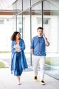 Young cute couple - a boy and a girl standing near a glass building. The couple spend time together. The guy speaks on the phone, Royalty Free Stock Photo