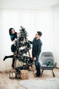 Young cute couple decorate a Christmas tree on Christmas Eve