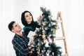 Young cute couple decorate a Christmas tree on Christmas Eve