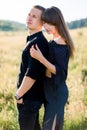Young cute couple in love, wearing stylish black clothes, posing outdoor in summer meadow. Sensual romantic portrait of Royalty Free Stock Photo