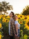 Young cute couple standing back to back and holding hands in a sunflower field Royalty Free Stock Photo