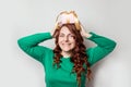 Young cute curly girl in a green sweater and holds a gift box on her head, smiling, looking at the camera. Holiday card with copy Royalty Free Stock Photo