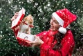 The girl takes kitten out of the box surprised and delighted and it`s snowing. Young cute European woman in red Santa hat gets