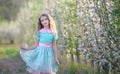 Young cute girl in Apple blossom garden plays with dress