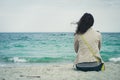 Young cute girl with curly hair sitting on an empty beach Royalty Free Stock Photo
