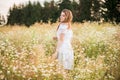 young cute girl,Tender dreamy in love, in a field with daisies. in dress and wicker hat. hot sunny summer, sunset in the