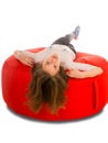 Young cute girl lying on round shape red beanbag chair Royalty Free Stock Photo