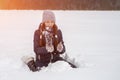 Young cute girl sits in the snow and makes a ball for a snowman. Artistically colored photography