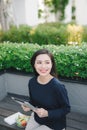 A young cute girl sitting in the park working scrolling a tablet Royalty Free Stock Photo