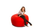 Young cute girl sitting on round shape red beanbag chair Royalty Free Stock Photo