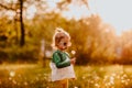 Young cute girl in sun glasses walking on a glade with dandelions. Sunset