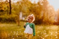 Young cute girl in sun glasses walking on a glade with dandelions. Sunset.