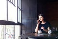 Young cute girl talking on the phone in cafe.