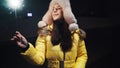 Young cute girl in a winter fur hat and yellow jacket in a festive mood. Sparkling burning sparklers in hand with flying sparks.