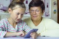 Young cute granddaughter teaching grandmother how to use smartphone at home Royalty Free Stock Photo