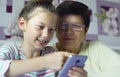 Young cute granddaughter teaching grandmother how to use smartphone at home