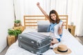 Young cute happy Asian girl finished packing suitcase luggage on bed in bedroom, ready to go abroad solo trip Royalty Free Stock Photo