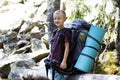 Young cute happy child boy with big tourist backpack on sunny rocks background. Tourism, hiking and active lifestyle concept Royalty Free Stock Photo