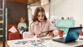 A young cute lady with brown straight hair well-dressed sitting at a table with her tablet and a colleague working on a